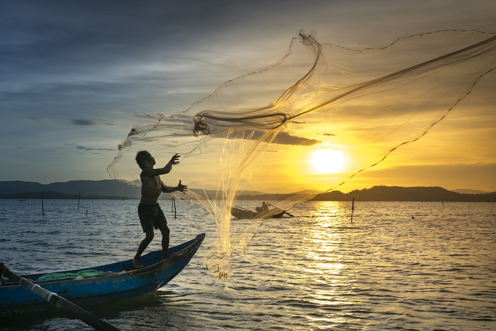 Fisherman throwing Fish Net on Lake